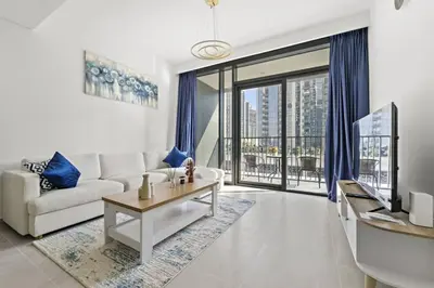 a living room with a white couch and a tv at Luxury 1BR apartment at Creek Edge Tower 2 in Dubai