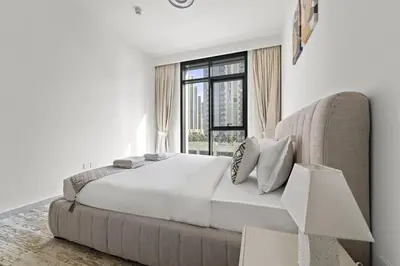 a white bedroom with a large bed and a window at Luxury 1BR apartment at Creek Edge Tower 2 in Dubai