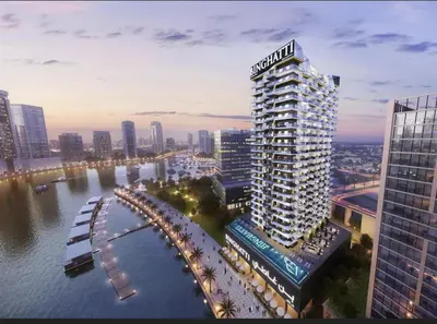 a tall building with a sign on it next to a river at Lux Apartment with huge private Lounge I Burj & Canal View in Dubai