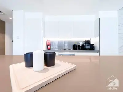 a white kitchen with two cups on a counter at High End 1Bedroom with Balcony & View Dubai in Dubai