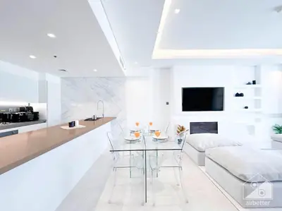 a white kitchen with a glass table and a couch at High End 1Bedroom with Balcony & View Dubai in Dubai