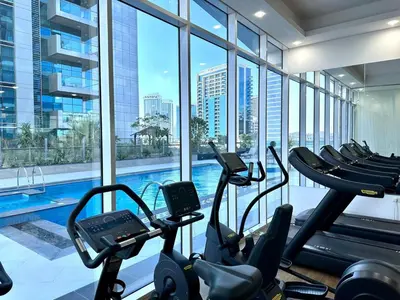a gym with a swimming pool in a building at Modern Furnished Studio with Canal View , High Floor in Dubai
