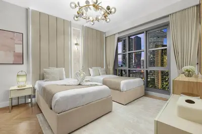 a bedroom with two beds and a chandelier at Burj Khalifa View 2BR Steps from Dubai Mall & Metro in Dubai