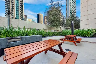 a wooden bench and two picnic tables on a patio at Burj Khalifa View 2BR Steps from Dubai Mall & Metro in Dubai