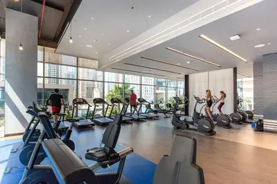 a gym with a bunch of treadmills and people in it at Jumeirah Living Marina Gate - Golf & Skyline Views with Pool & Gym in Dubai