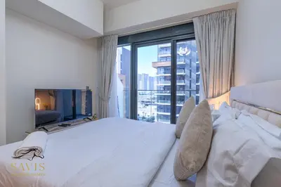 a bedroom with a large white bed with a large window at Savis Homes - Azizi Riviera 43 - Chic Studio Near Downtown and Business Bay in Dubai