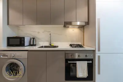 a kitchen with a sink and a stove and a microwave at Savis Homes - Azizi Riviera 43 - Chic Studio Near Downtown and Business Bay in Dubai