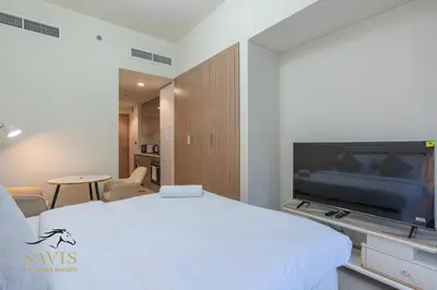 a bedroom with a white bed and a tv at Savis Homes - Azizi Riviera 43 - Chic Studio Near Downtown and Business Bay in Dubai
