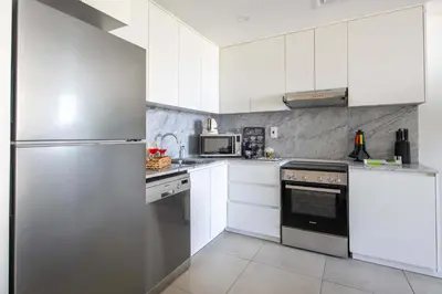 a kitchen with white cabinets and a stainless steel refrigerator at Frank Porter - Lamtara 3 in Dubai