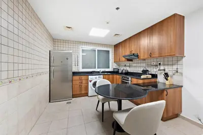 a kitchen with wooden cabinets and a table and chairs at Cozy 1-Bedroom Apartment In Princess Tower in Dubai