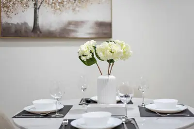 a table with a vase with white flowers on it at Cozy 1-Bedroom Apartment In Princess Tower in Dubai