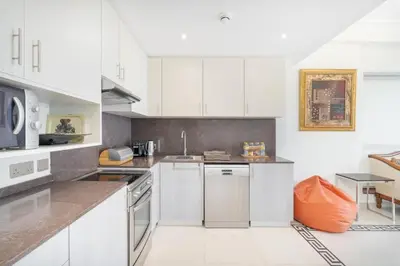 a kitchen with white cabinets and an orange pillow at JBR Marina View - 2BR Apartment in Dubai