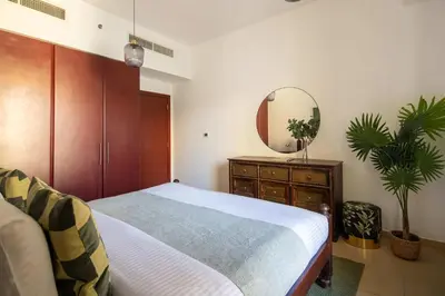 a bedroom with a bed and a dresser and a mirror at Frank Porter - Shams 4 in Dubai