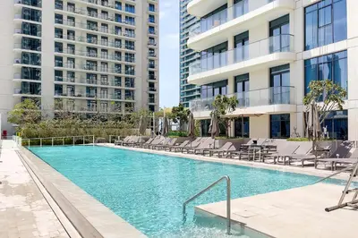 a swimming pool with lounge chairs and a building at Marina Vista Private Beach 2BR in Dubai