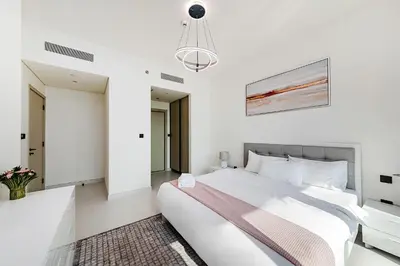 a white bedroom with a large bed and a chandelier at Marina Vista Private Beach 2BR in Dubai