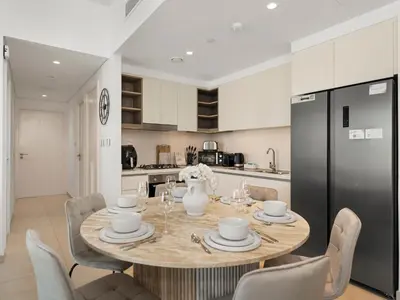 a kitchen with a table with chairs and a black refrigerator at Blissful Stays - Luxury Two Bedroom Apartment at Downtown Views II- 5 min walk to Dubai Mall, Burj Khalifa with Infinity Pool in Dubai