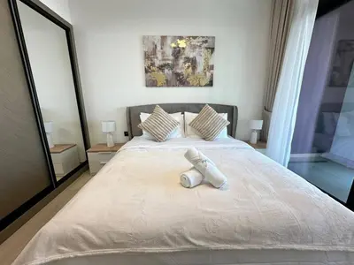 a large white bed with a towel on it at Stylish 1br Apartment Jvc Balcony Parking in Dubai