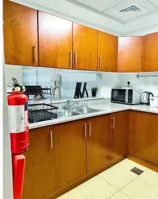 a kitchen with wooden cabinets and a red fire hydrant at Charming & Comfortable 1BR Jumeirah Bay X1 JLT in Dubai