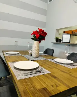 a wooden table with plates and a vase with red flowers at Charming & Comfortable 1BR Jumeirah Bay X1 JLT in Dubai