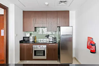 a kitchen with wooden cabinets and a stainless steel refrigerator at Silkhaus Burj Khalifa & Zaabeel View in Burj Daman in Dubai