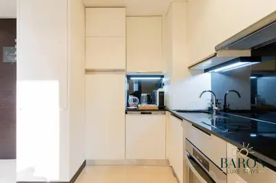 a kitchen with white cabinets and black counter tops at The Charming in Dubai