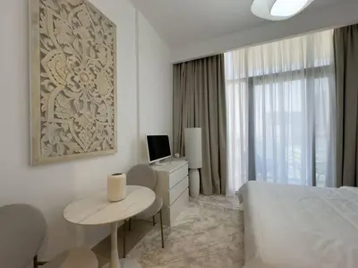 a bedroom with a bed and a table and a television at Newly Furnished Studio Azizi Riviera 37 Al Meydan in Dubai