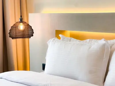 a bed with a white pillow and a lamp at 1-BR Gem with Luxe Amenities in JVC in Dubai