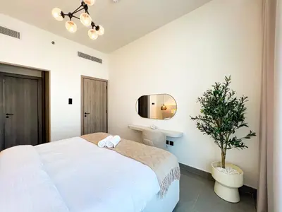 a bedroom with a white bed and a potted tree at 1-BR Gem with Luxe Amenities in JVC in Dubai
