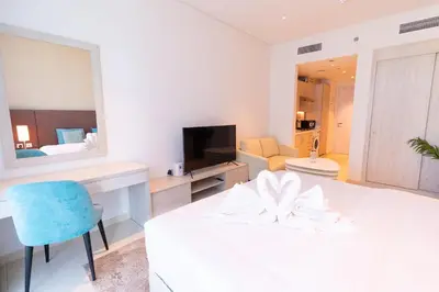 a white room with a table and a blue chair at Seven Palm Residences Palm Jumeirah by Happy Season in Dubai