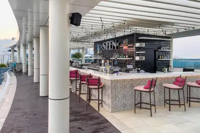 a bar with pink chairs and a counter on a building at Seven Palm Residences Palm Jumeirah by Happy Season in Dubai