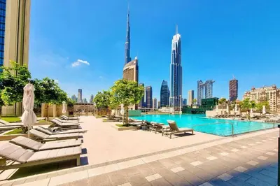 a swimming pool with lounge chairs and a city skyline at Downtown Dubai views 2 tower 1 in Dubai