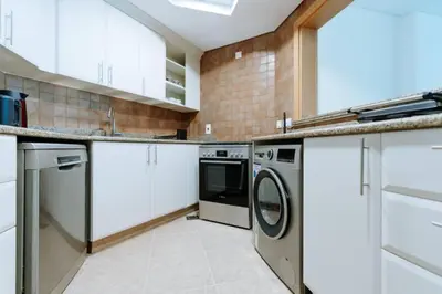 a kitchen with white cabinets and a washer and dryer at Elegant 1BR beach access with Ocean Views, Palm in Dubai