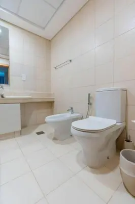 a white bathroom with a toilet and a sink at Elegant 1BR beach access with Ocean Views, Palm in Dubai