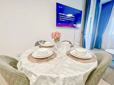 a white table with plates and wine glasses on it at Luxury 2 Bedroom in the Nook 1 next to Metro Energy in Dubai