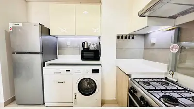 a small kitchen with a washer and a stove at Modern 1-Bedroom La Perla Apartment JVC with Infinity Pool & Kids’ Zone in Dubai