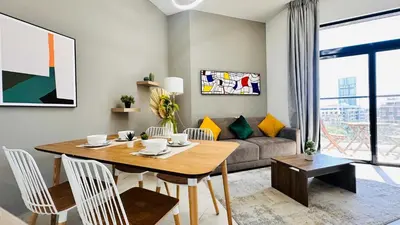 a living room with a table and a couch at Modern 1-Bedroom La Perla Apartment JVC with Infinity Pool & Kids’ Zone in Dubai