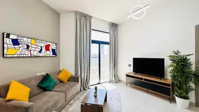 a living room with a couch and a flat screen tv at Modern 1-Bedroom La Perla Apartment JVC with Infinity Pool & Kids’ Zone in Dubai