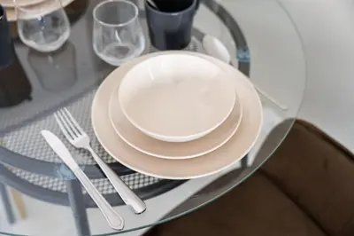 a glass table with plates and utensils on it at Urban Designer Apt - Family Friendly in Dubai