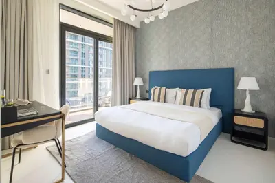 a bedroom with a blue bed and a desk and window at Frank Porter - Marina Vista tower 2 in Dubai