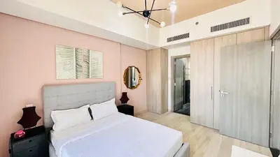 a bedroom with a white bed and a sliding glass door at Premium 1-Bedroom Perla Apartment in JVC | Infinity Pool & Kids’ Play Area in Abu Dhabi
