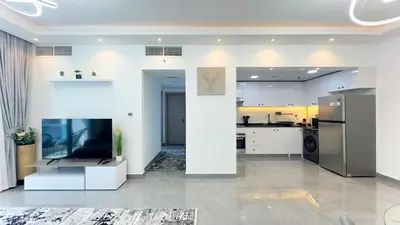 a kitchen with white cabinets and a tv in a room at Dubai Marina- Cozy 2BHK Apartment in Dubai
