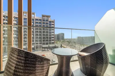 a table and chairs on a balcony with a view of a city at Studio Azizi Riviera 24 Community View in Dubai