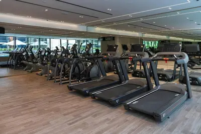 a gym with rows of cardio equipment in a building at Stylish 1br Jvc Spacious Layout Pool View in Dubai