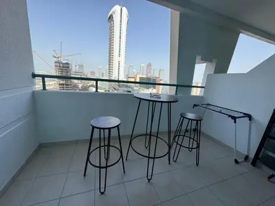 a balcony with three bar stools and a view of a city at Marina Crown 1 BR Modern Apartment Full Sea View in Dubai