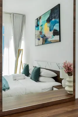 a living room with a white bed with green pillows at ShoresInn - Aesthetic Stay with Dubai Marina View in Dubai