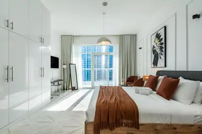a white bedroom with a large bed with a wooden table at ShoresInn - Aesthetic Stay with Dubai Marina View in Dubai