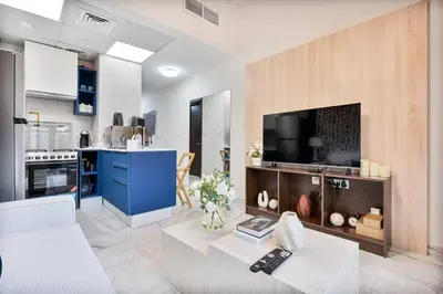 a living room with a tv and a kitchen at Serene Studio APT with Pool and Gym in Dubai
