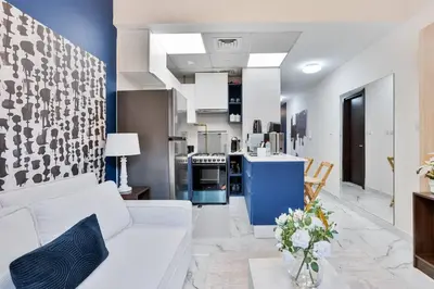 a living room with a white couch and a kitchen at Serene Studio APT with Pool and Gym in Dubai