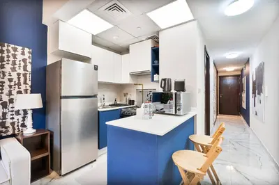 a kitchen with blue and white cabinets and a refrigerator at Serene Studio APT with Pool and Gym in Dubai