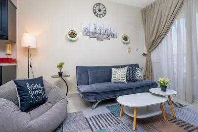 a living room with a blue couch and a table at 2-Bedroom Marina Skyline View in JLT in Dubai
